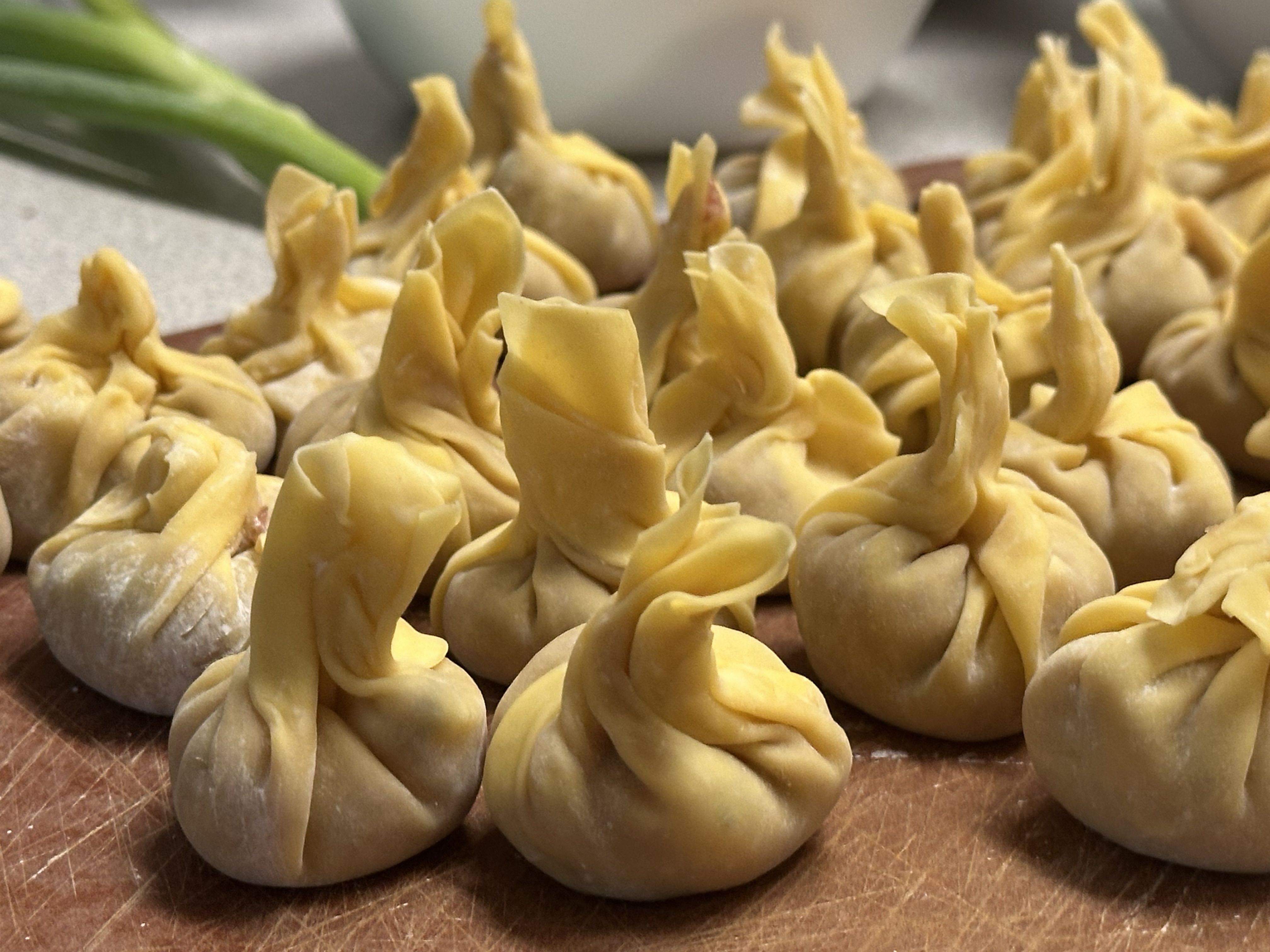 Photo of nearly 2 dozen finished wontons fully in focus, front and center